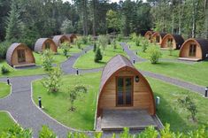 small wooden cabins in the middle of a grassy area with trees and bushes around them