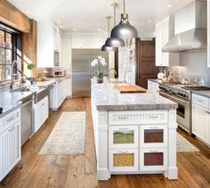 a large kitchen with white cabinets and wood flooring, an island in the middle