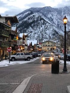 cars are parked on the street in front of buildings with mountains in the back ground