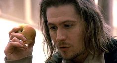 a man with long hair holding an apple