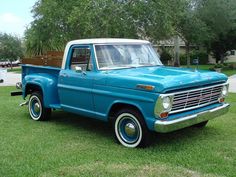 an old blue pickup truck parked in the grass