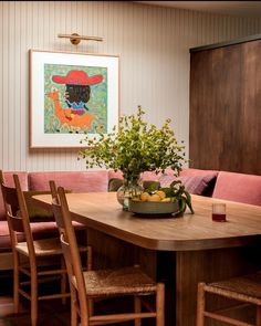 a wooden table with chairs around it and a bowl of fruit sitting on top of it