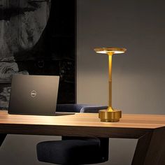 a laptop computer sitting on top of a wooden desk next to a lamp and chair