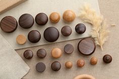 several different types of wooden buttons on a table next to a piece of cloth and a feather