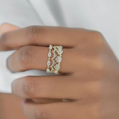 a woman's hand wearing a gold ring with three rows of diamonds on it