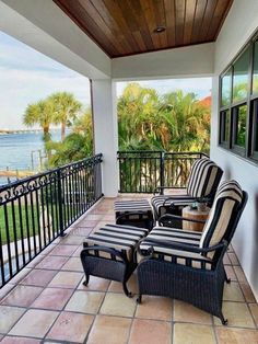 two chairs sitting on top of a tiled floor next to a balcony with palm trees