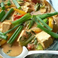 a bowl filled with tofu, green beans and veggies next to a spoon