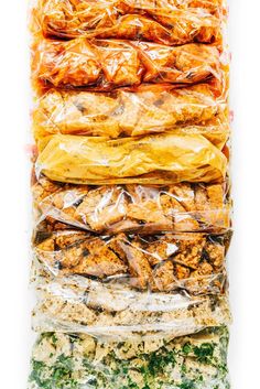 an assortment of food wrapped in plastic on top of each other, including meats and vegetables