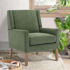 a green chair sitting on top of a rug next to a potted plant