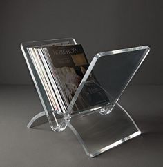 an acrylic magazine rack with magazines on it's sides and the front section folded open