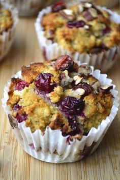 several muffins with cranberries and nuts in them on a wooden table