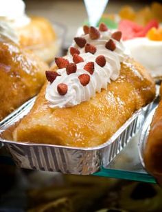 several pastries in tins with frosting and strawberries sitting on top of each other