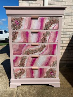 a pink and white dresser sitting on top of a sidewalk