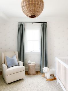 a baby's room with a crib, rocking chair and window