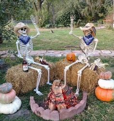 two skeletons sitting on hay bales with pumpkins