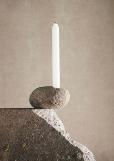 a white candle sitting on top of a rock