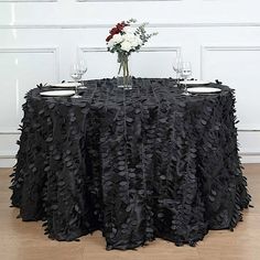 a black table cloth with flowers and wine glasses sitting on top of it in front of a white door