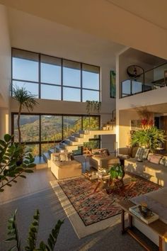 a living room filled with lots of furniture and large windows overlooking the mountains in the distance