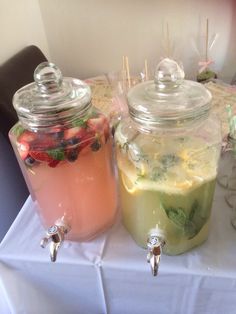 two jars filled with drinks sitting on top of a table next to eachother