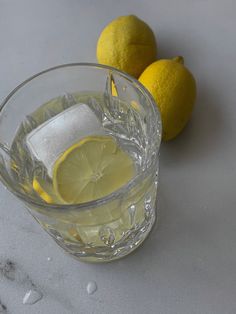 two lemons are sitting next to a glass of water