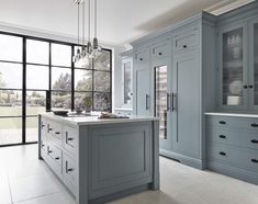 a large kitchen with blue cabinets and marble counter tops, along with an island in the middle