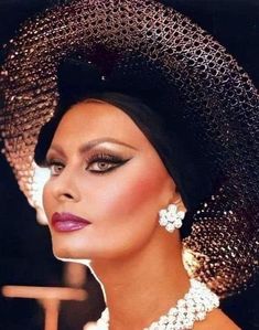 a woman wearing a black hat and pearls on her head with a large diamond necklace