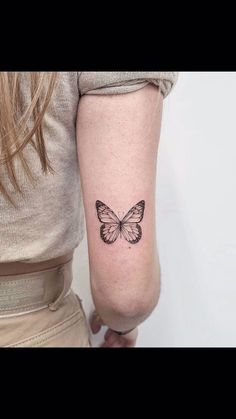 a woman's arm with a small butterfly tattoo on the left side of her arm