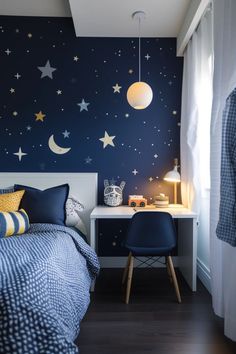 a bedroom decorated in blue and yellow with stars on the wall, bedding and desk