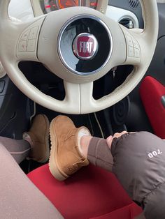 a person sitting in the driver's seat of a car with their feet on the steering wheel