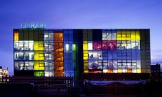 the library is lit up at night with colorful lights on it's facade and windows