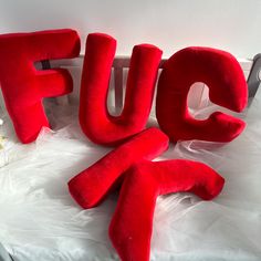 the word fuc spelled out in red letters on top of a white sheeted surface