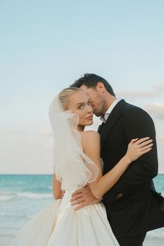 a bride and groom embracing on the beach