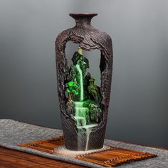 a vase with water pouring out of it on a wooden table next to a gray wall