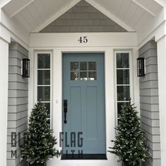 a blue front door with two potted evergreen trees on the side and number 45