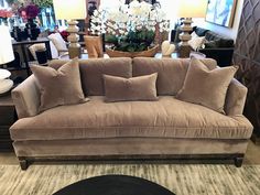 a living room filled with lots of furniture and pillows on top of a rug next to a coffee table