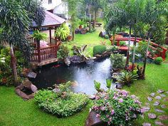 the garden is full of plants and flowers, including an umbrella over a small pond