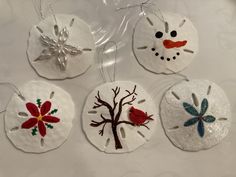 four handmade christmas ornaments with snowman, tree and bird designs on white paper