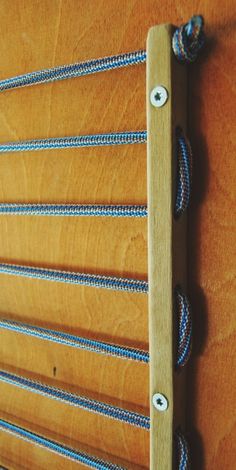 a close up of a wooden wall with ropes attached to the wood and metal hooks