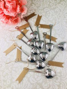 a bunch of silver spoons sitting on top of a table next to a pink flower