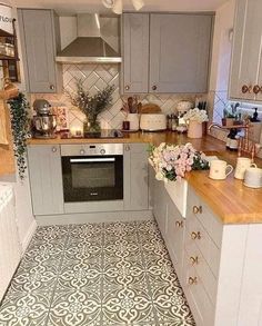 a kitchen with grey cabinets and white tile flooring is pictured in this image, there are flowers on the counter