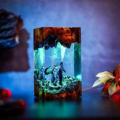 a glass box with an image of godzilla in it on a table next to flowers