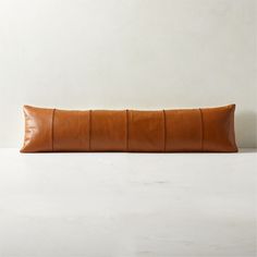 a brown leather pillow sitting on top of a white table