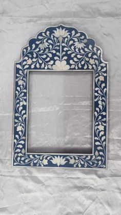 an ornate blue and white frame with flowers on the outside, sitting on a sheet of paper