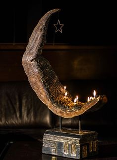 a wooden crescent with candles in it sitting on a table next to a leather couch