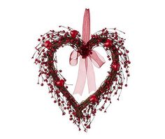 a heart shaped decoration with red berries and pink ribbon hanging from it's side