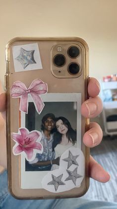 a person holding up a cell phone with an image of two women and stars on it