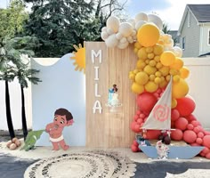 a birthday party with balloons and decorations on the ground, including a tall wooden sign that says mia