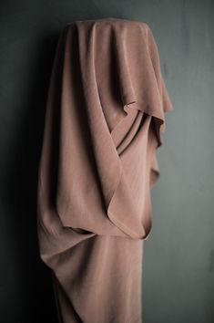 the back of a woman's dress hanging up against a wall with her head covered by a blanket