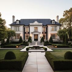 a large white house surrounded by hedges and trees