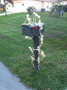 a mailbox with skeleton decorations on it in the grass next to a sidewalk and house